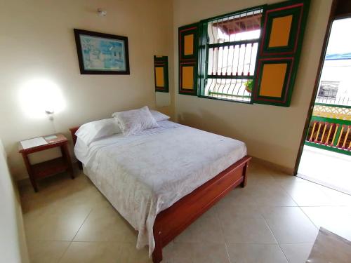 a small bedroom with a bed and two windows at Balcones del Parque Jardin in Jardin