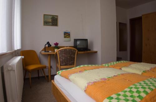 1 dormitorio con 2 camas y escritorio con TV en Landgasthof Kemter en Dröbischau