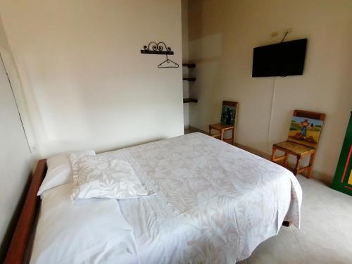 a bedroom with a white bed and a flat screen tv at Balcones del Parque Jardin in Jardin