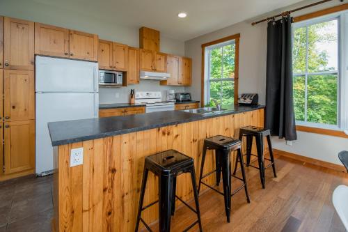 a kitchen with wooden cabinets and a counter with stools at La plus belle vue du secteur - La Forteresse in Petite-Rivière-Saint-François