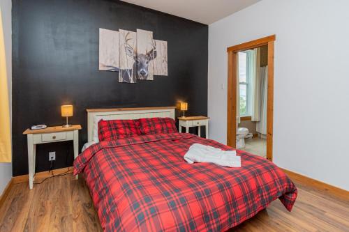 a bedroom with a bed with a red plaid blanket at La plus belle vue du secteur - La Forteresse in Petite-Rivière-Saint-François
