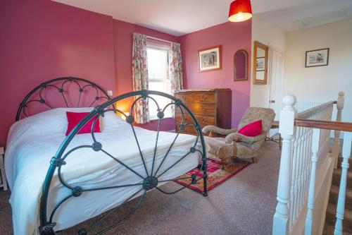 a bedroom with a bed with a red wall at The Annexe at Clarendon in Bovey Tracey