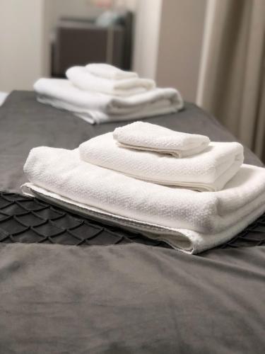 - un ensemble de serviettes blanches assises sur un lit dans l'établissement La Maison de la Douce Heure, 4 appartements climatisés avec jardin au centre ville proche des Thermes, à Lons-le-Saunier