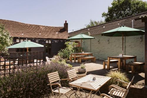 a patio with tables and chairs and umbrellas at Cantley House Hotel - Wokingham in Wokingham