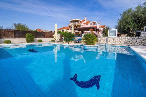 a large swimming pool with blue water in front of a house at Villa Dalmatina Zadar mit Pool in Zadar