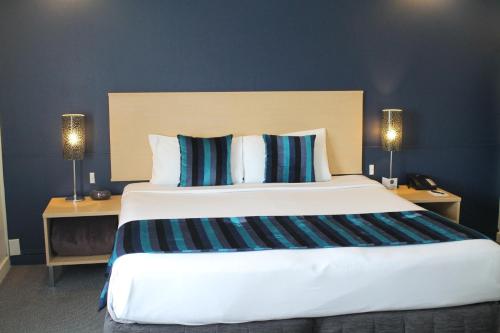 a large bed in a hotel room with two lamps at Willis Wellington Hotel in Wellington