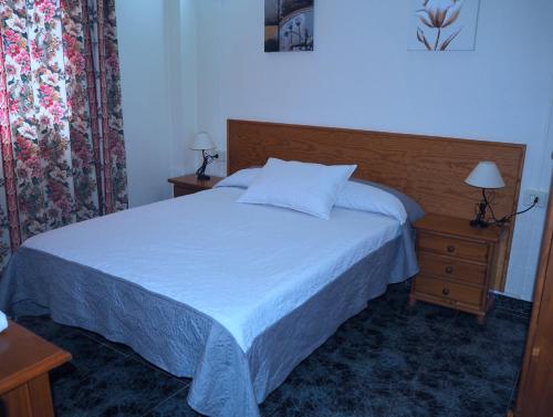 1 dormitorio con 1 cama y mesita de noche con colcha blanca en apartamentos la villa 2, en San Sebastián de la Gomera