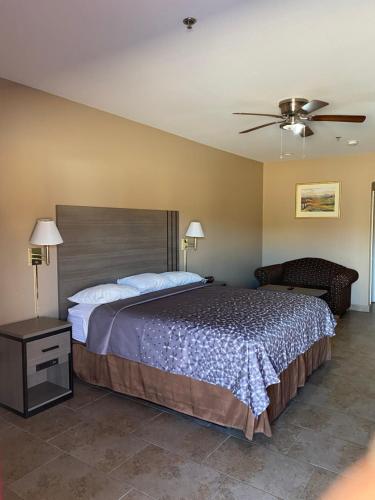 1 dormitorio con 1 cama grande y ventilador de techo en Los Fresnos Inn and Suites, en Los Fresnos
