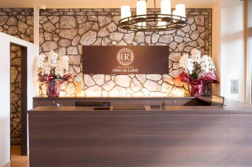 a hotel lobby with a reception desk with flowers in vases at Global Resort ONO de LUNE in Hatsukaichi