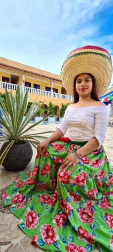 a girl wearing a sombrero and a green dress with flowers at Hotel Campo Real Plus Tamasopo in Tamasopo