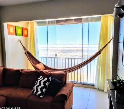 a living room with a couch and a hammock in front of a window at Apto 2 quartos em Arroio do Silva in Arroio do Silva