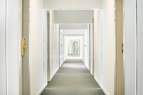 a hallway with white walls and a long hallway with white doors at Hotel Sansi Park in Lleida