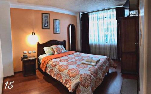 a bedroom with a large bed and a window at Hotel Los Ilinizas in Latacunga