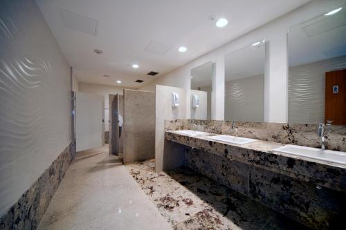 a bathroom with three sinks and two mirrors at Quality Hotel Vitória in Vitória