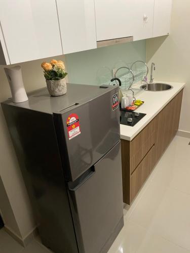 een keuken met een zwarte koelkast en een wastafel bij Cozy Studio at Kozi Square in Kuching