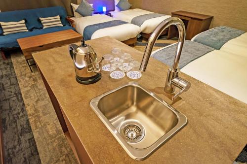 a kitchen counter with a sink next to a bed at Beautemps in Osaka