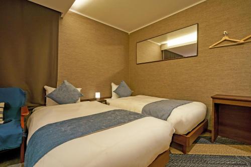 a hotel room with two beds and a mirror at Beautemps in Osaka