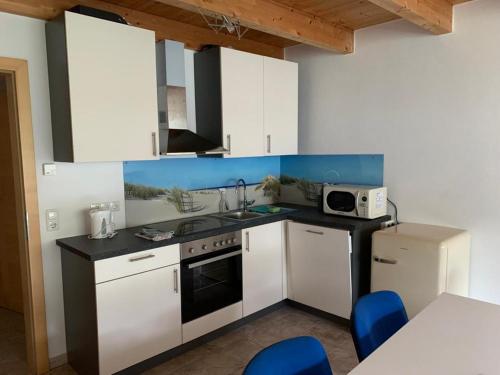 eine Küche mit weißen Schränken, einer Spüle und einer Mikrowelle in der Unterkunft Apartment Katalin in Murau