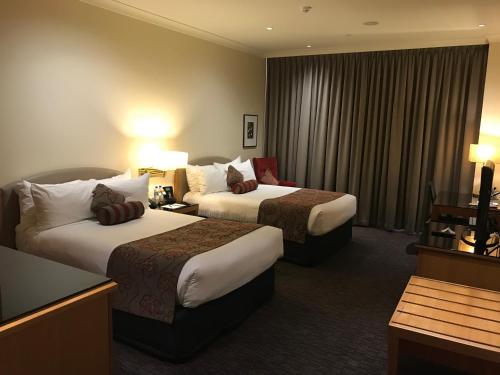 a hotel room with two beds and two lamps at Duxton Hotel Perth in Perth