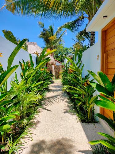 a pathway leading to a house with palm trees at Kalea Villas in Kuta Lombok