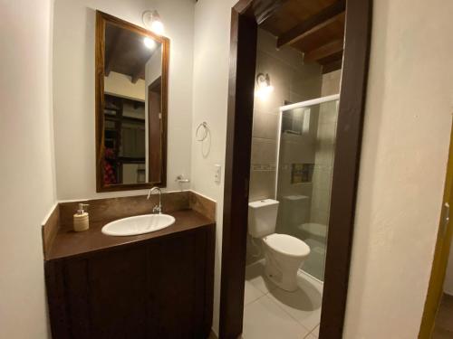 y baño con lavabo, aseo y espejo. en Pousada Morrison, en Praia do Rosa