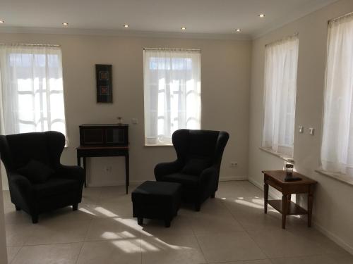 sala de estar con 2 sillas, mesa y ventanas en Großzügiges Appartement -ruhig und doch zentral, en Odenthal