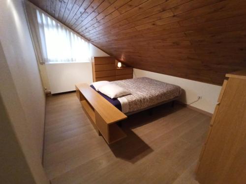 a small bed in a room with a wooden ceiling at A casa da Balbina in Betanzos