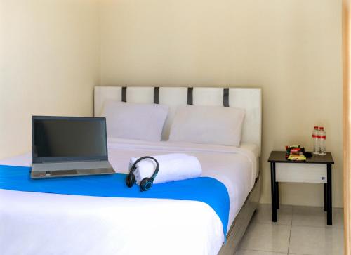 a bedroom with a bed with a laptop and headphones at City Residence Kutai 32 in Surabaya