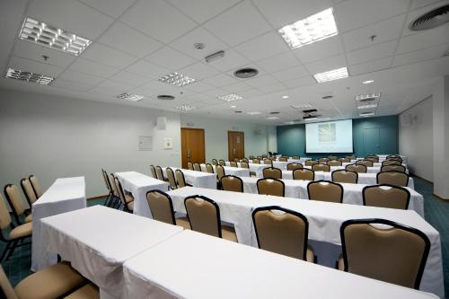 a conference room with tables and chairs and a screen at Quality Hotel Vitória in Vitória