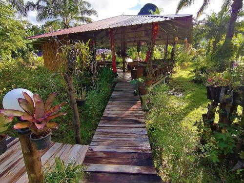a wooden walkway in a garden with a pavilion at Koom Kachanaan in Ban Nong Thale
