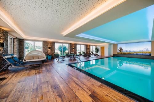 a swimming pool in a house with a large window at Hotel Taxerhof in Radstadt