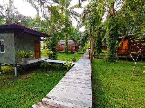 a walkway leading to a cabin in a resort at Koom Kachanaan in Ban Nong Thale