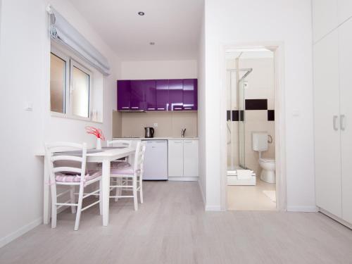 a kitchen with white cabinets and a table and chairs at Apartments F & P in Dubrovnik