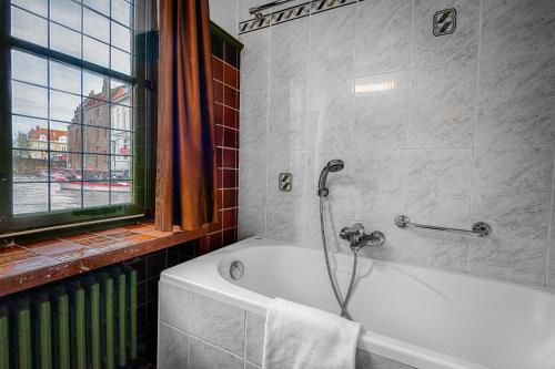 a bath tub sitting next to a window in a bathroom at Hotel Bourgoensch Hof in Bruges