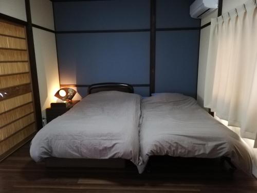 新宫市ゲストハウス みふね的卧室内的一张床铺,卧室内有蓝色的墙壁
