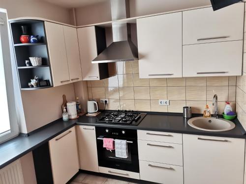 uma cozinha com armários brancos, um fogão e um lavatório em Sunny apartment Kėdainiai em Kėdainiai