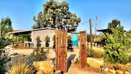 a garden with a wooden gate and a building at Finca Vidandrei CASA EUCALIPTO in Valle de Guadalupe