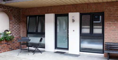 ein Gebäude mit schwarzen Türen sowie einem Tisch und Stühlen in der Unterkunft Apartment "Lyon" in Korschenbroich