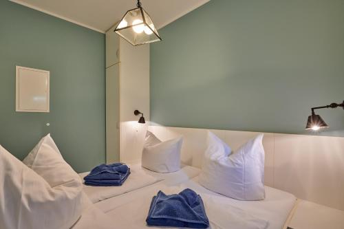 a white bed with white pillows and blue towels on it at Laguna Seeappartements in Neukieritzsch