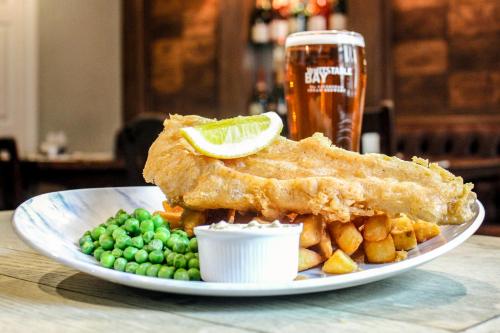 a plate with fish and chips and peas and a glass of beer at The Millers Arms Inn in Canterbury