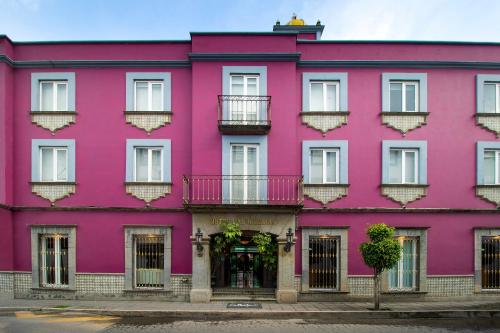 喬盧拉的住宿－Collection O Las Iglesias, Cholula，粉红色的建筑,设有白色的窗户和阳台