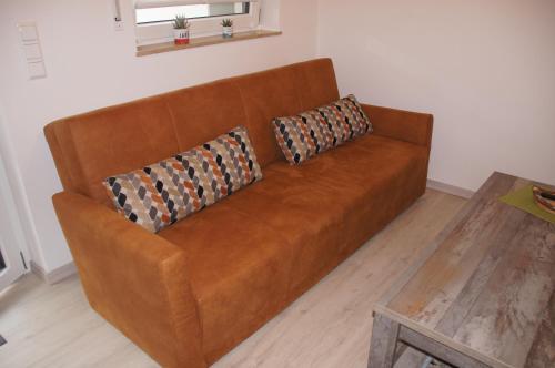 a brown couch with two pillows on it in a living room at Ferienwohnung Jurastein in Burglengenfeld