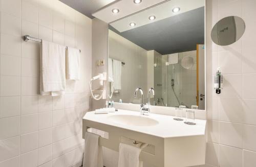 a white bathroom with a sink and a mirror at Parkhotel Berghölzchen in Hildesheim