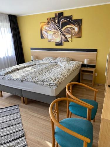 a bedroom with a bed and two chairs at Rómahegy Rendezvényház in Kaposvár