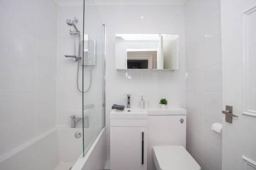 a white bathroom with a shower and a sink at The Warwick Apartment in Greenock