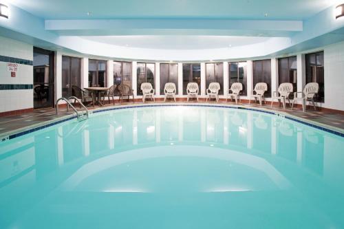 a swimming pool with chairs and a table at Holiday Inn Express & Suites Colorado Springs North, an IHG Hotel in Colorado Springs