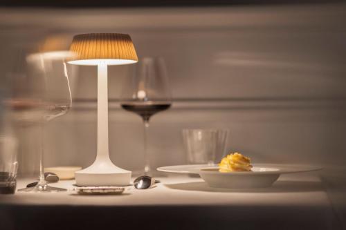a table with a plate of food and a lamp and wine glasses at Palais Gentile Matino in Matino
