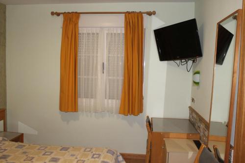 1 dormitorio con 1 cama y TV de pantalla plana en Hostal Burbia en Villafranca del Bierzo