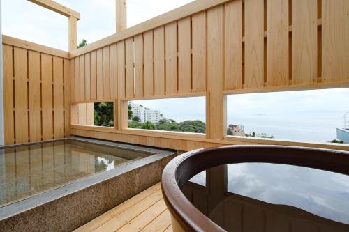 a swimming pool in a room with windows at Ishinoya Atami - TKP Hotels & Resorts in Atami