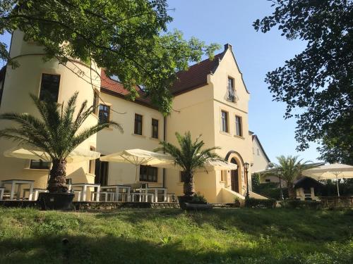 a large white building with palm trees in front of it at Parkschlößchen in Maasdorf